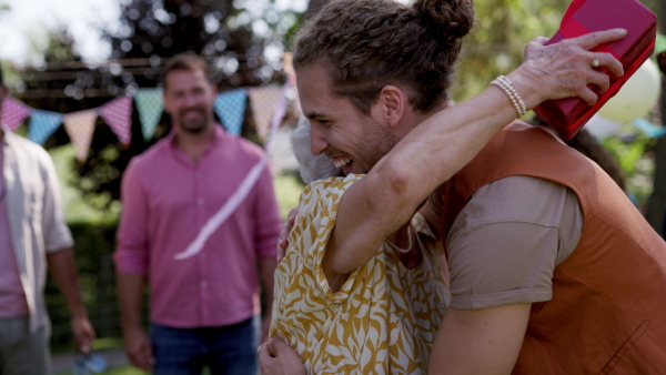 Garden birthday party for senior lady. Beautiful senior birthday woman hugging man.