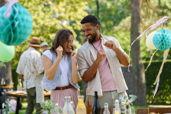 Friends talking, dancing and having fun at a summer grill garden party.