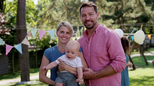 Young family with a baby at a family garden party. Father, mother, and a small child at birthday party.