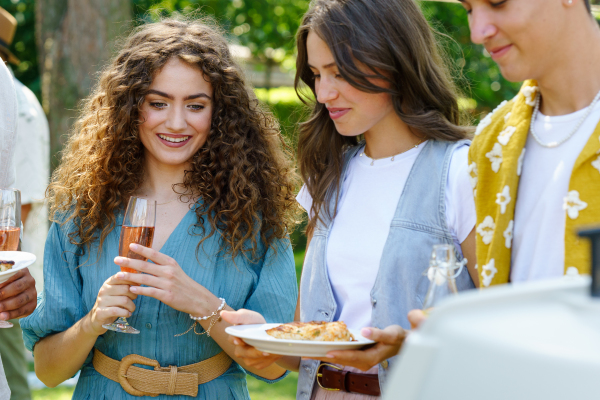 Friends and family talking and eating barbeque specialties at a summer grill garden party.