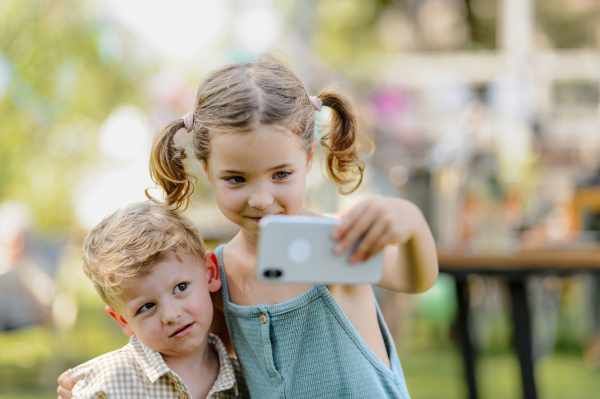 Cousins taking a selfie at a family garden party. Family reunion at a garden barbecue party.