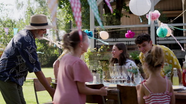 Family chatting, laughing, and having fun at the party table during a summer garden party.