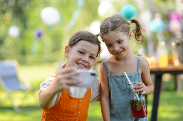 Cousins taking a selfie at a family garden party. Family reunion at a garden barbecue party.