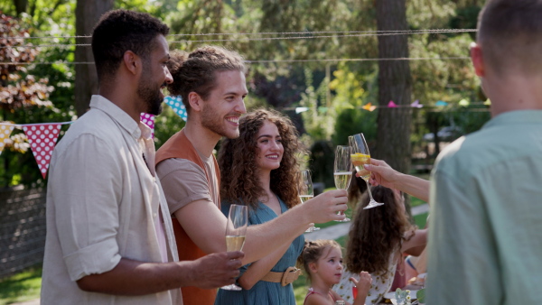 Friends chatting, laughing, and having fun at the party table during a summer garden party.