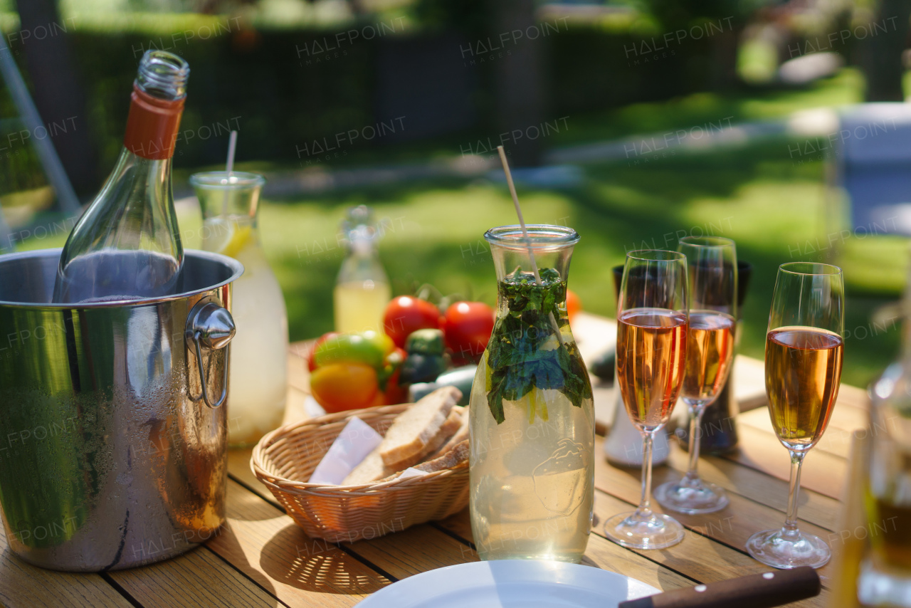 Close up shot of refreshing drinks at summer garden party. Table setting with glasses, lemonade and bottles of summer wine.