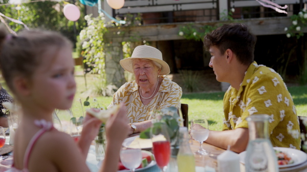 Family chatting, laughing, and having fun at the party table during a summer garden party.