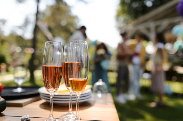 Close up shot of wine in glassed at summer garden party. Table setting with glasses, lemonade and bottles of summer wine.