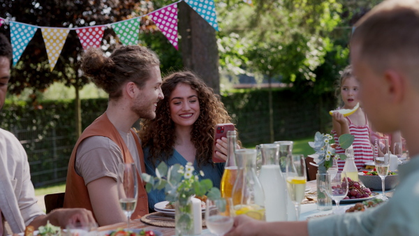 Video of couple sitting at the table with family and friends at the family garden party. A family gathering to celebrate a birthday.