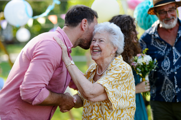 Garden birthday party for senior lady. Beautiful senior birthday woman receiving birthday wishes.