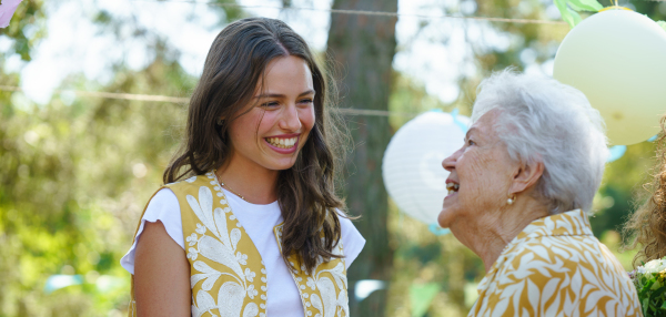 Mature granddaughter and grandmother reunite after a long time, talking and having fun. Family gathering at a garden party. Banner with copy space.