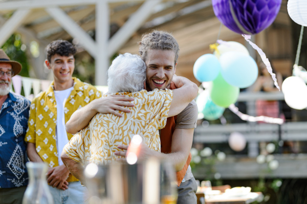 Garden birthday party for senior lady. Beautiful senior birthday woman receiving gift from grandson.