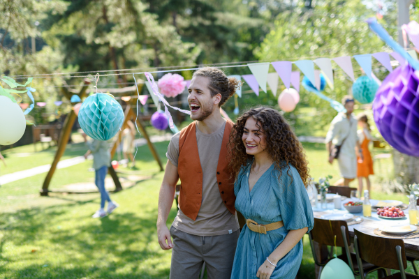 Portrait of couple talking with family and friends at the family garden party. A family gathering to celebrate a birthday.