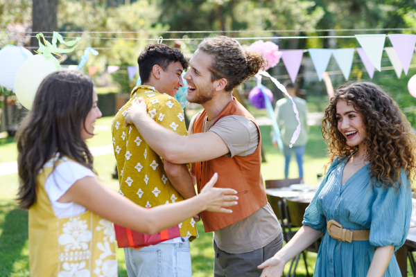 Friends reunite after a long time apart. Men and women embracing, happy to meet at a garden party.