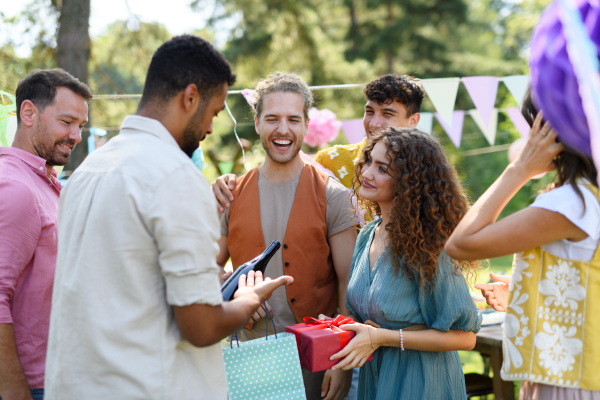 Garden birthday party. Beautiful birthday girl receiving gifts from friends and family.