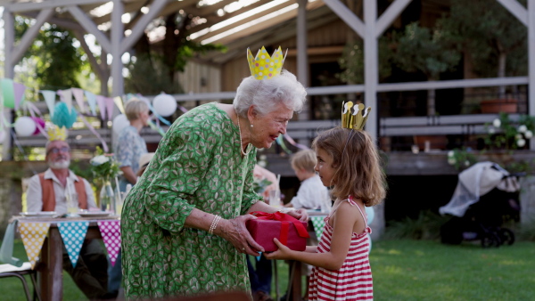 Garden birthday party for senior lady. Beautiful senior birthday woman receiving gifts from grandchildren.