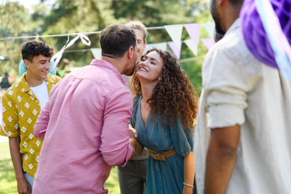 Friends reunite after a long time apart. Man and woman embracing, happy to meet at a garden party.