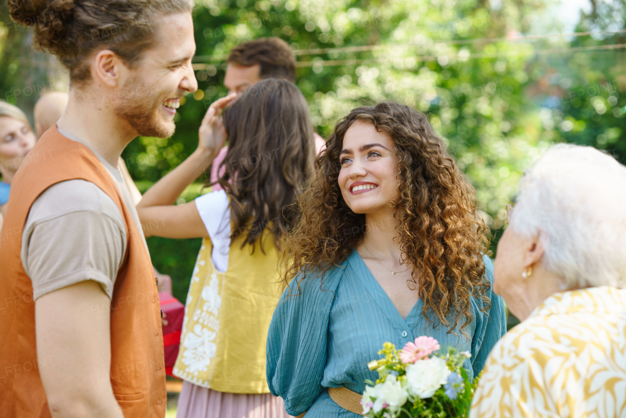 Friends and family talking at a summer bbq summer garden party. Granddaughter introducing her boyfriend to grandmother.