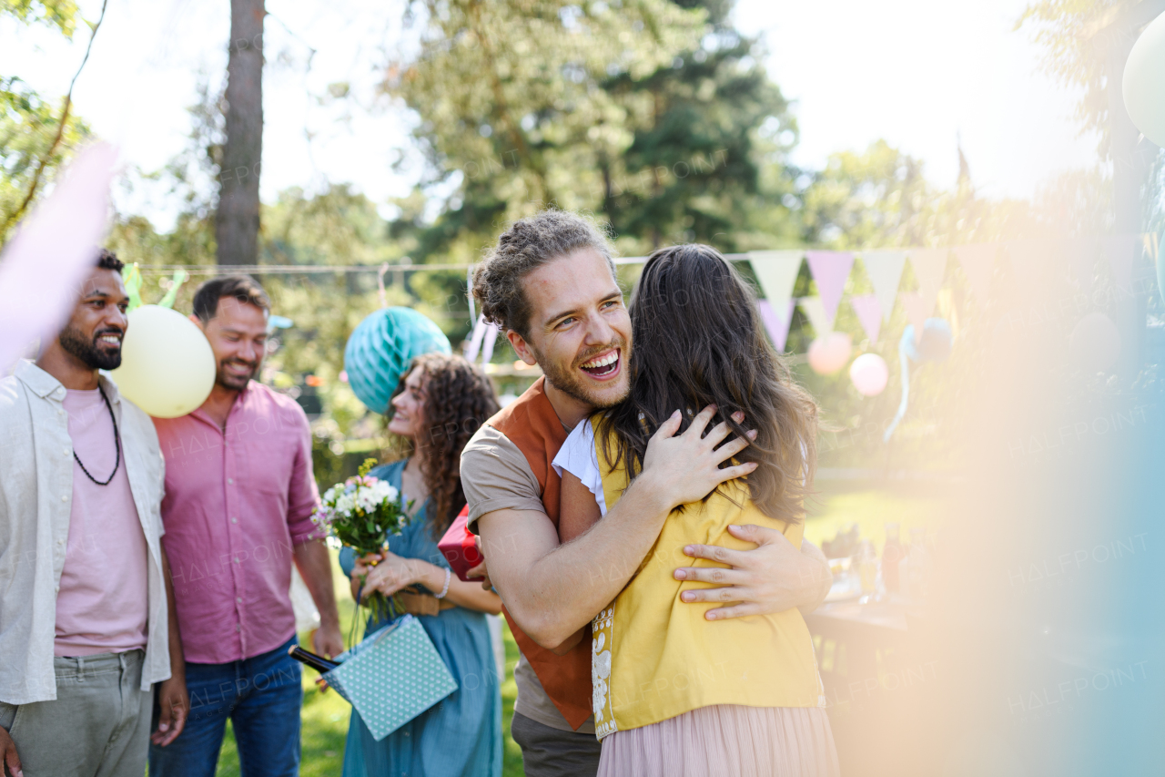 Friends reunite after a long time apart. Man and woman embracing, happy to meet at a garden party.