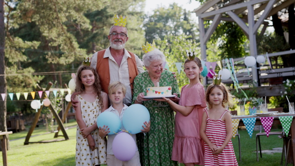 A family video at an outdoor summer garden party. Grandparents and grandkids standing and posing for a group photo. Multigenerational family.