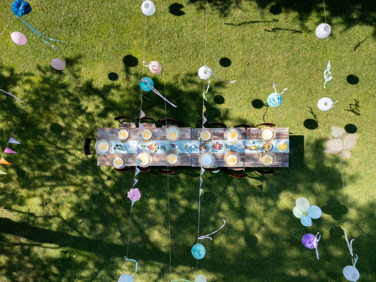 Top view of summer garden party in a beautiful garden. BBQ family gathering, with a set table and colorful decorations.