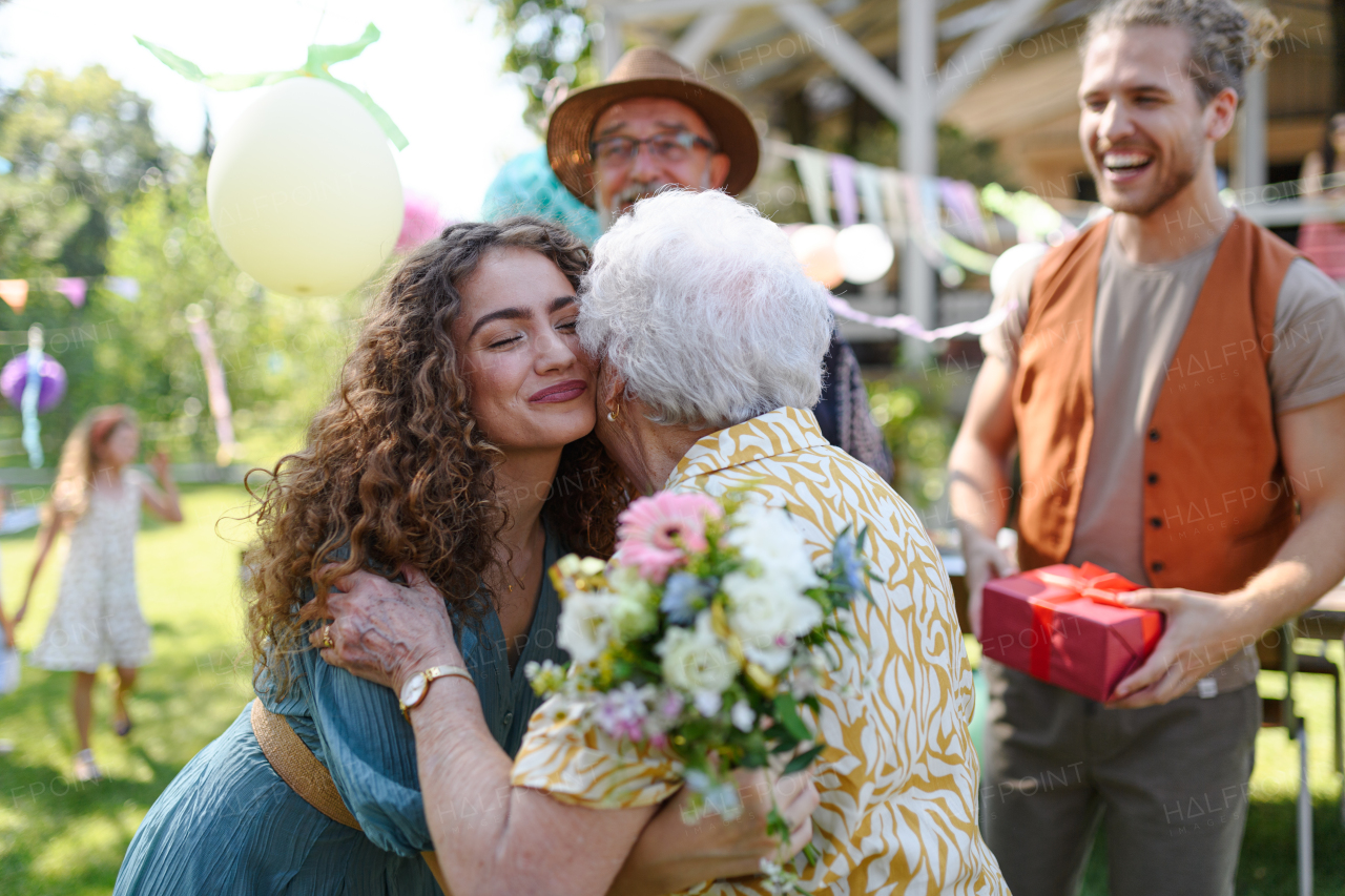 Garden birthday party for senior lady. Beautiful senior birthday woman hugging her granddaughter.