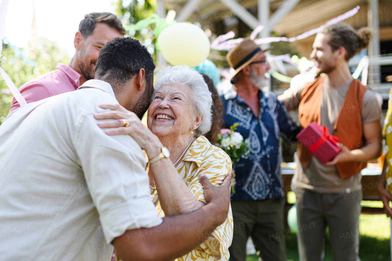 Garden birthday party for senior lady. Beautiful senior birthday woman hugging man.