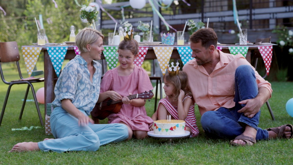 Garden birthday party with surprise for girl. Parents giving daughter presents, gifts and birthday cake as birthday surprise.