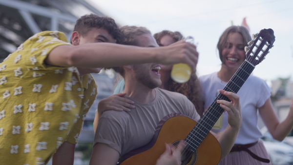 Friends taking selfie at a summer grill garden party. Handsome man playing at guitar at party.