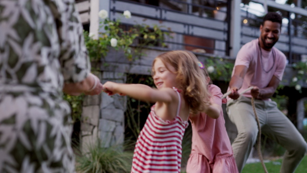 Grandparents have a tug of war with their granddaughters. Fun games at a family garden party.