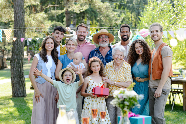 Family portrait at an outdoor summer garden party. Family and friends standing and posing for a group photo. Multigenerational family.