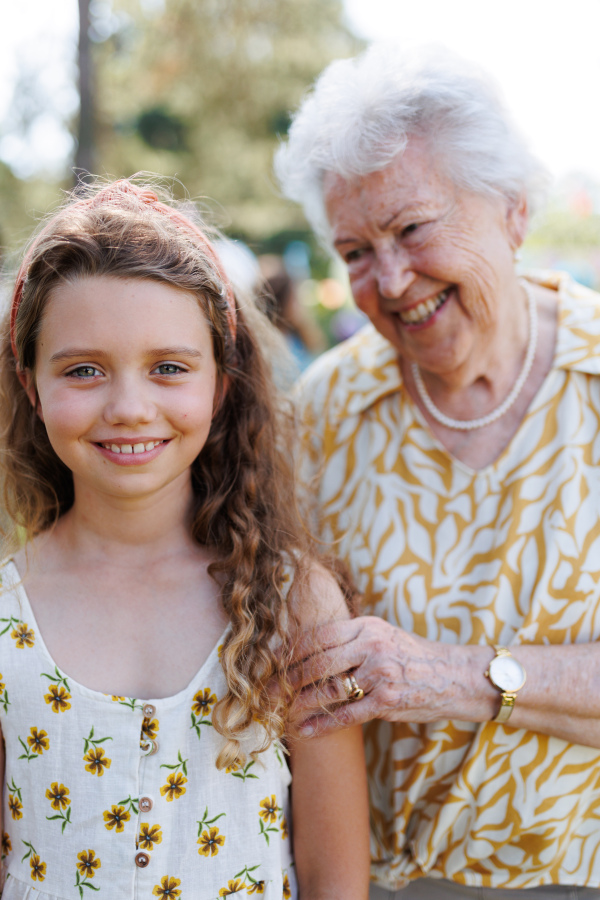 Portrait of young girl with grandmother at garden party. Love and closeness between grandparent and grandchild.