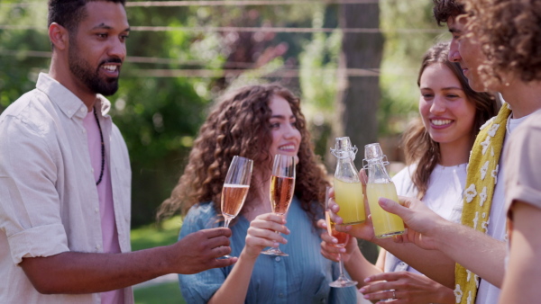 Friends chatting, laughing, and having fun at the party table during a summer garden party.