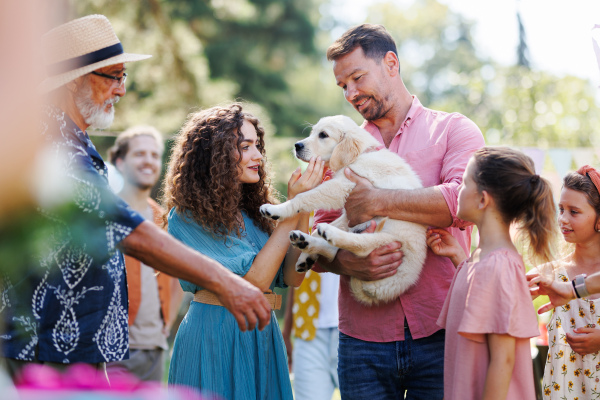 Garden birthday party for young girl. Beautiful birthday girl received a puppy as a birthday gift.