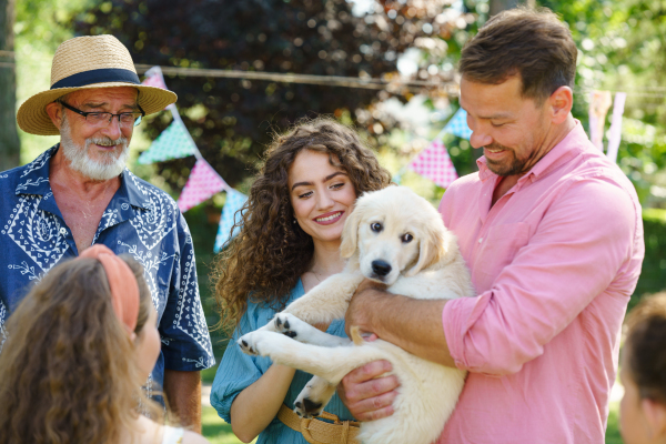 Garden birthday party for young girl. Beautiful birthday girl received a puppy as a birthday gift.