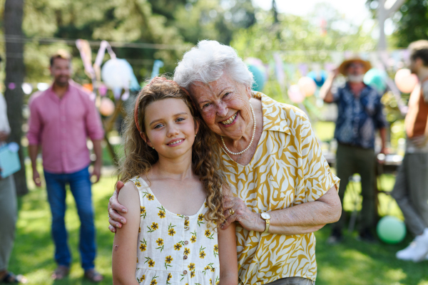 Portrait of young girl with grandmother at garden party. Love and closeness between grandparent and grandchild.