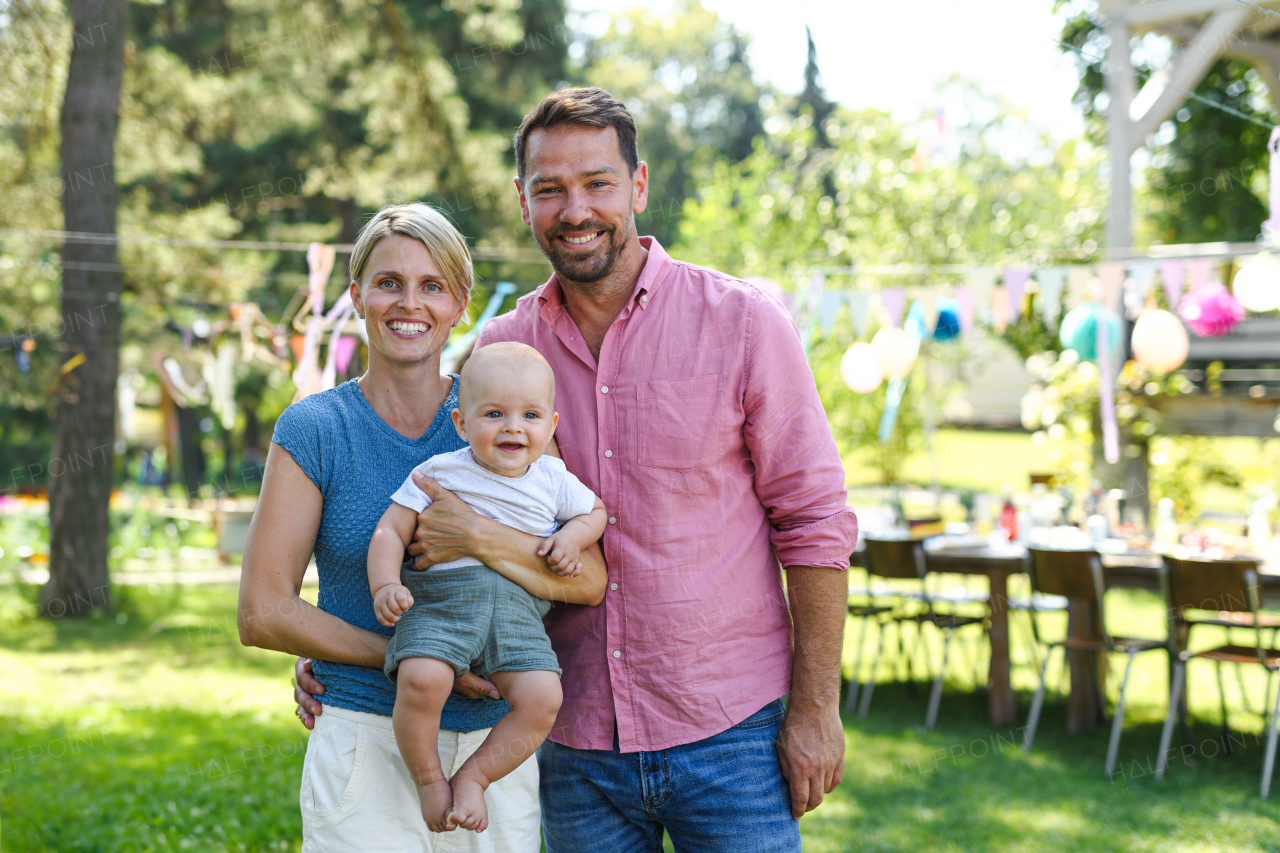 Young family with a baby at a family garden party. Father, mother, and a small child at birthday party.