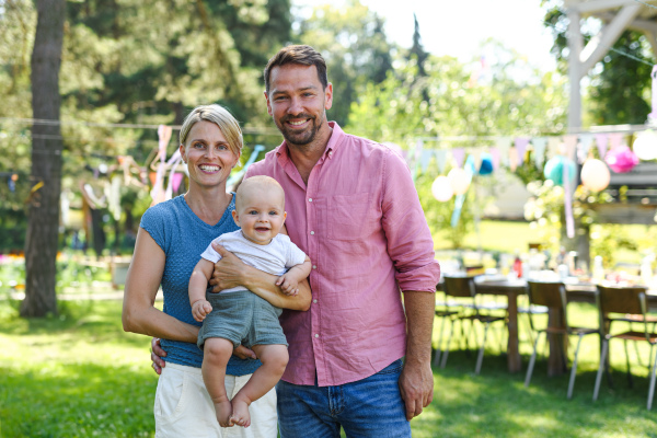 Young family with a baby at a family garden party. Father, mother, and a small child at birthday party.