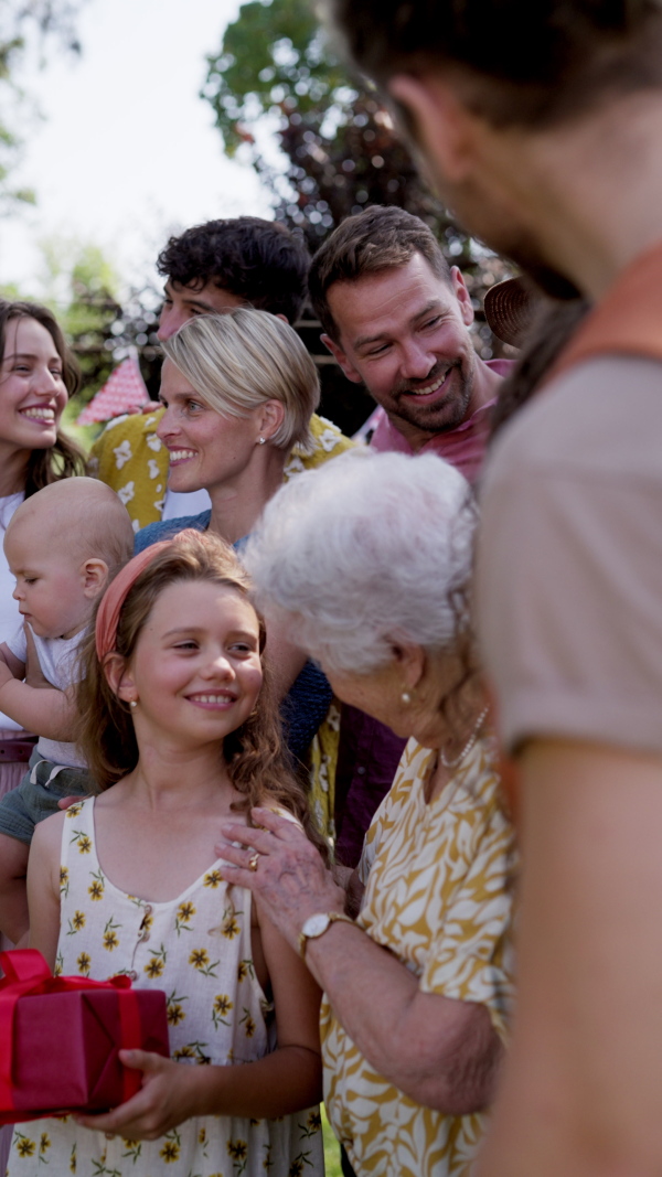 Family video at an outdoor summer garden party. Family and friends standing and posing for a group photo. Multigenerational family.