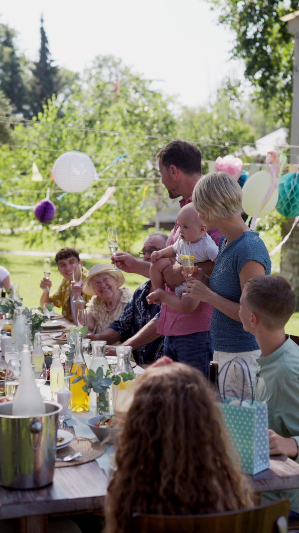 Family chatting, laughing, and having fun at the party table during a summer garden party.