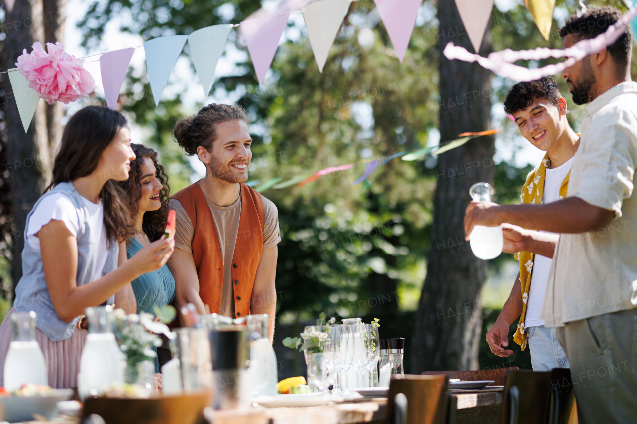 Friends and family talking, having fun and eating barbeque specialties at a summer grill garden party.