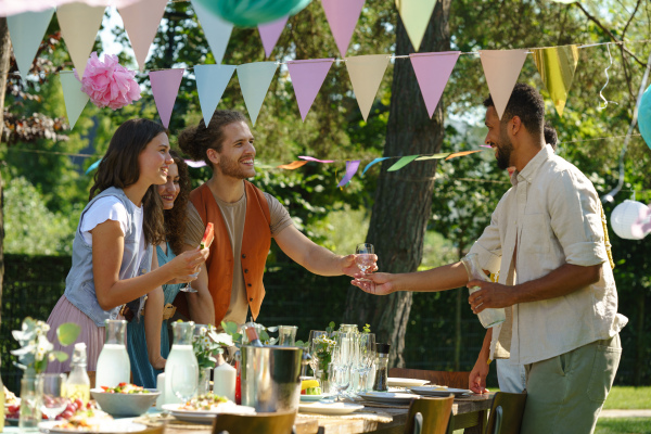 Friends and family talking, having fun and eating barbeque specialties at a summer grill garden party.