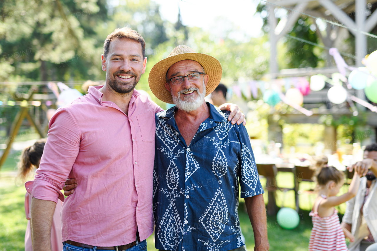 Portrait of an adult, mature son with his elderly father at a summer garden party outdoors. Concept of Father's Day and paternal love at any age.