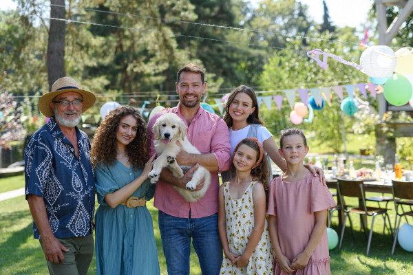 Family portrait at an outdoor summer garden party. Family and friends standing and posing for a group photo. Multigenerational family.