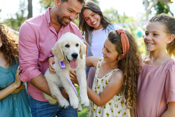 Garden birthday party for young girl. Beautiful birthday girl received a puppy as a birthday gift.