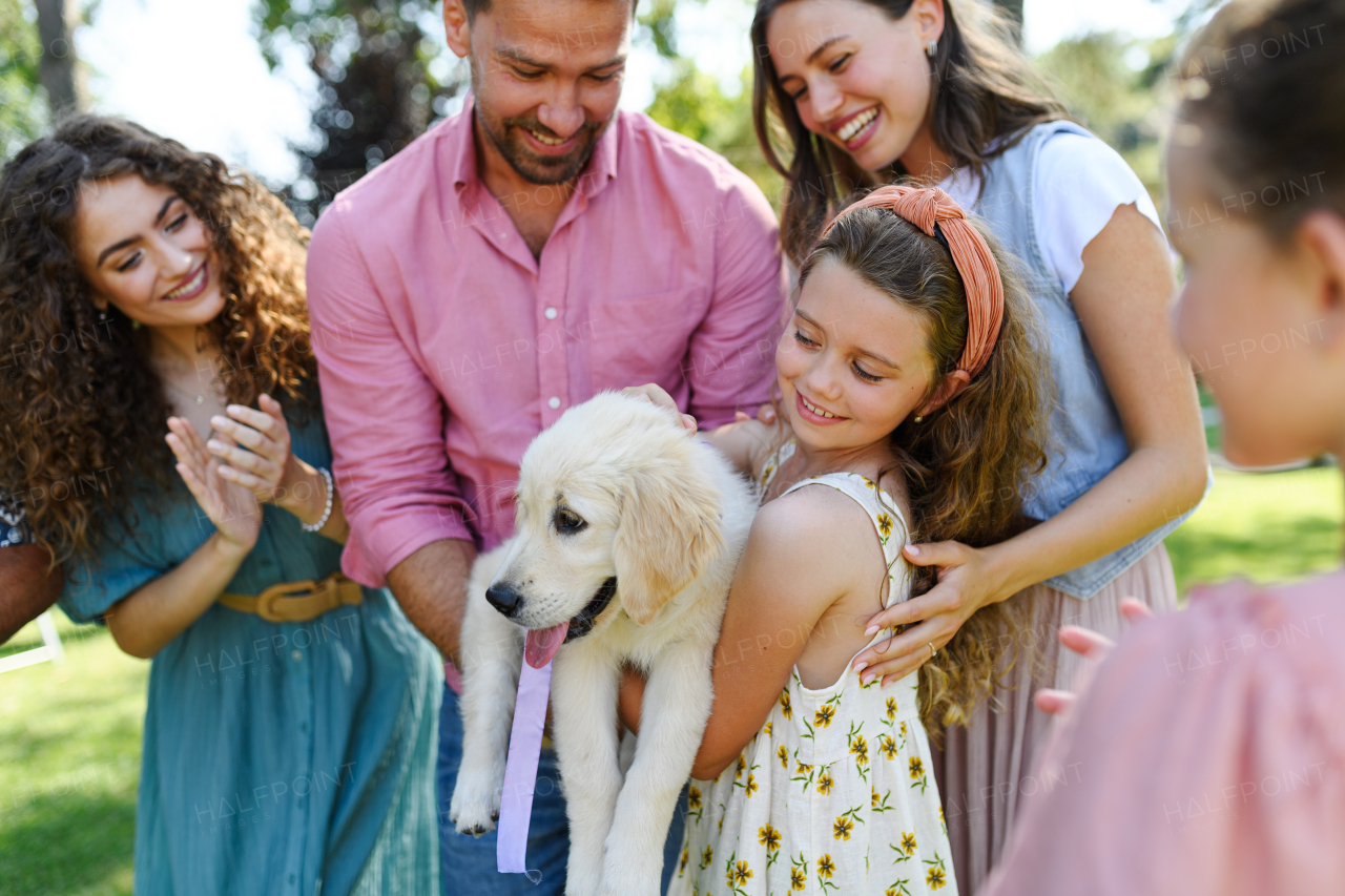 Garden birthday party for young girl. Beautiful birthday girl received a puppy as a birthday gift.