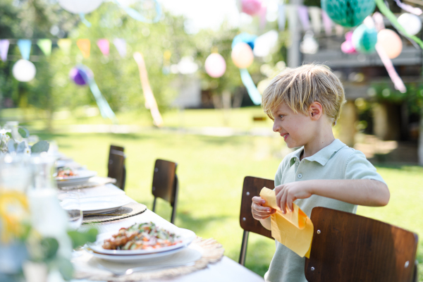 Hungry boy looking at a plate full of grilled dishes on the table. Summer garden party.