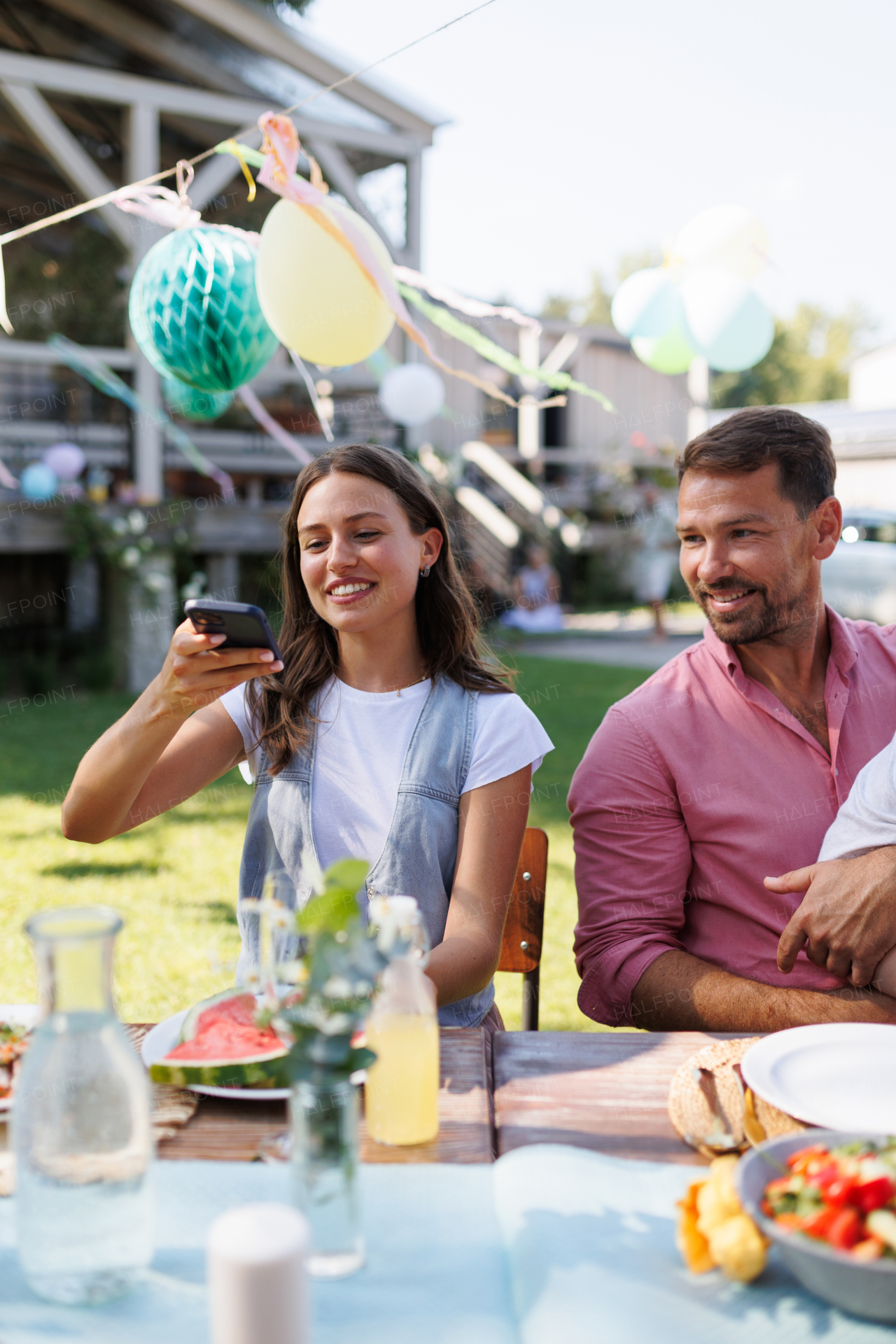 Woman taking a photo of her food with her smartphone at a garden party. Family bbq garden party.