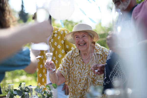 Family toast. Clinking glasses at summer garden party. Celebratory toast at the table. Big family garden bbq.