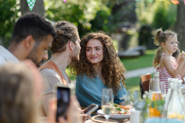 Portrait of couple sitting at the table with family and friends at the family garden party. A family gathering to celebrate a birthday.