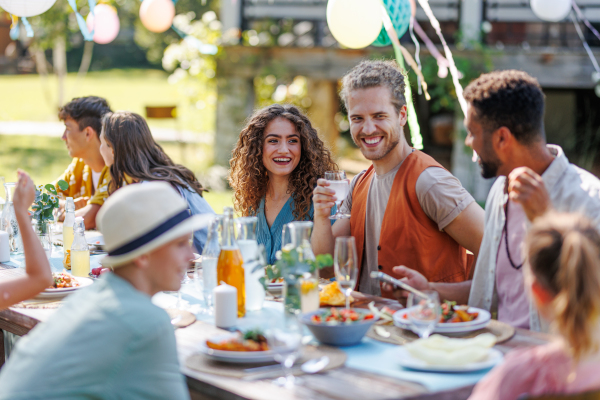 Portrait of couple sitting at the table with family and friends at the family garden party. A family gathering to celebrate a birthday.